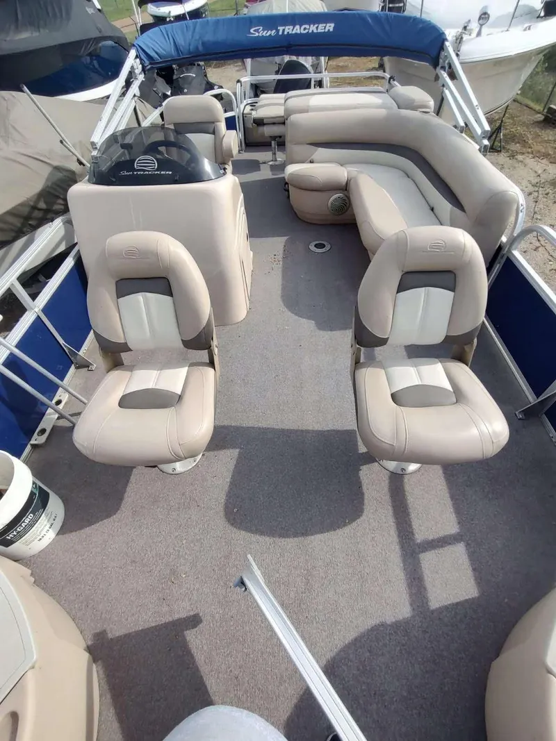 Slide: The Image of 2016 Sun Tracker Fishin' Barge 22 DLX interior with beige seating and blue canopy. - 17