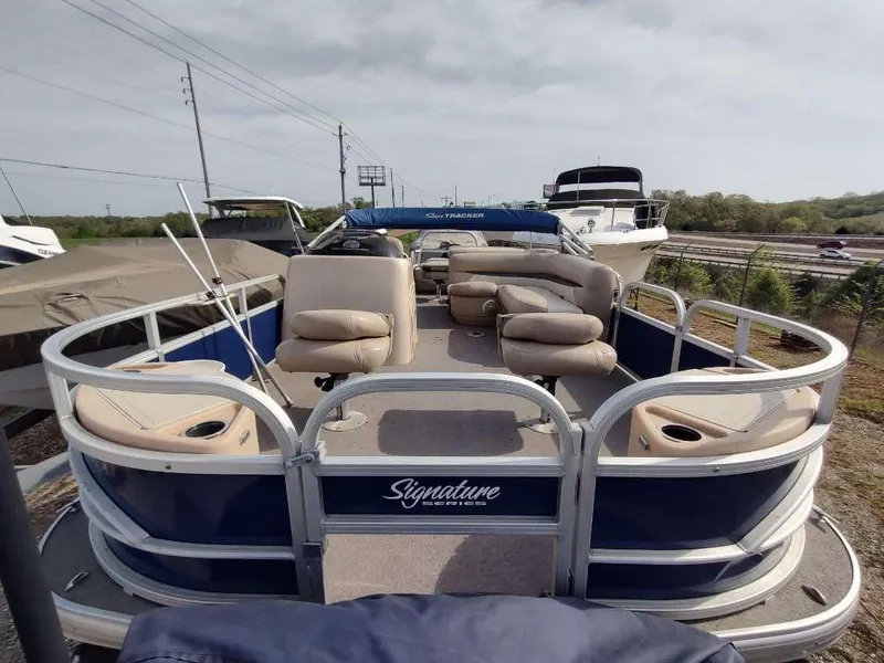 Slide: The Image of 2016 Sun Tracker Fishin' Barge 22 DLX pontoon boat with cushioned seating, docked outdoors. - 3