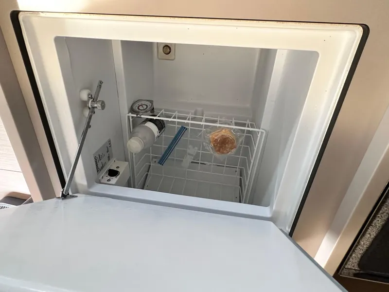 Slide: The Image of Freezer compartment in 2022 Beneteau Oceanis 46.1 yacht, containing a wrapped item and a bottle. - 49