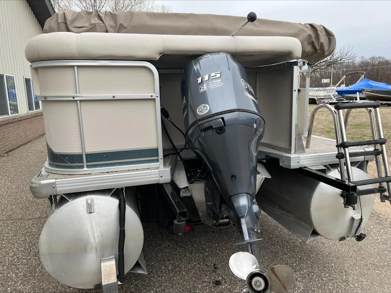 Slide: The Image of 2003 Premier 250 Escapade pontoon boat with 115 HP outboard motor, docked on land. - 6