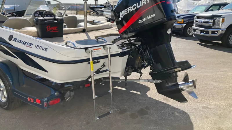 Slide: The Image of 2004 Ranger 180 Reata boat with Mercury Optimax engine and ladder, parked outdoors. - 2