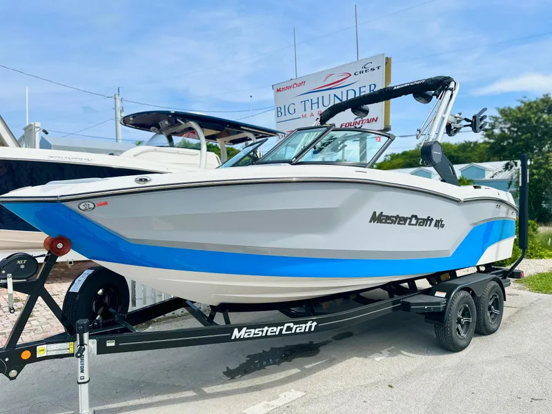 Slide: The Image of 2023 MasterCraft NXT21 boat on trailer, displayed outdoors with blue accents. - 1
