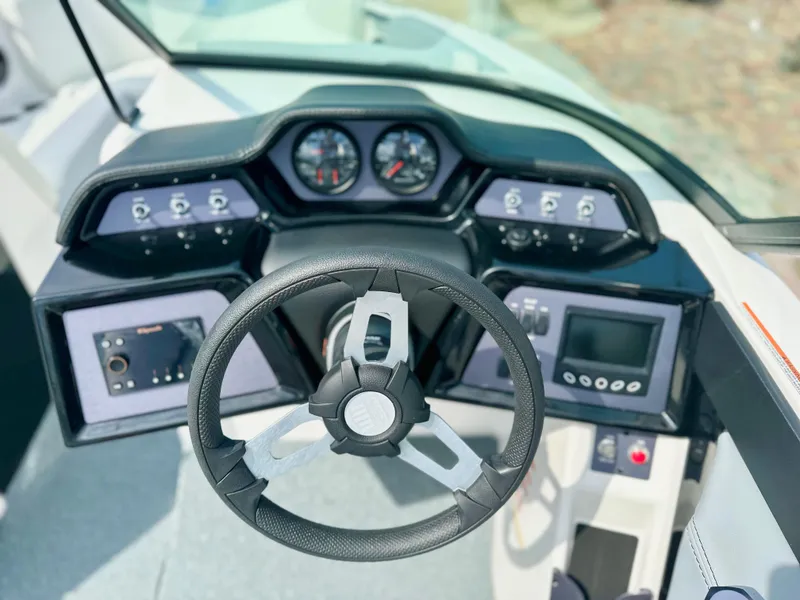 Slide: The Image of 2023 MasterCraft NXT21 boat dashboard with steering wheel and control panels. - 16