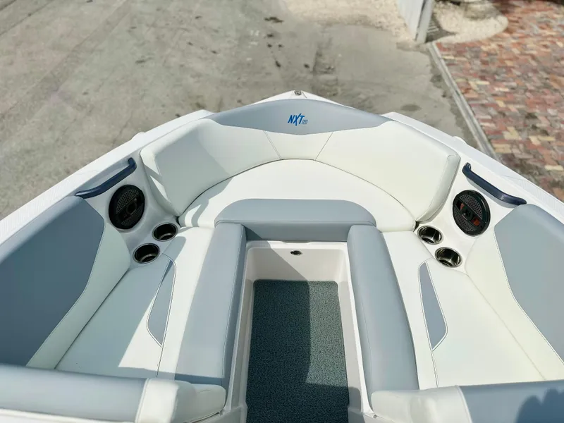 Slide: The Image of 2023 MasterCraft NXT21 boat interior with white and gray seating, cup holders, and speakers. - 26