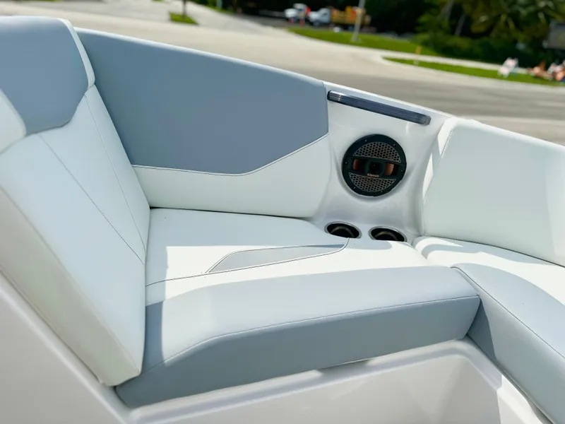 Slide: The Image of 2023 MasterCraft NXT21 boat interior with gray and white seating, speaker, and cup holders. - 27