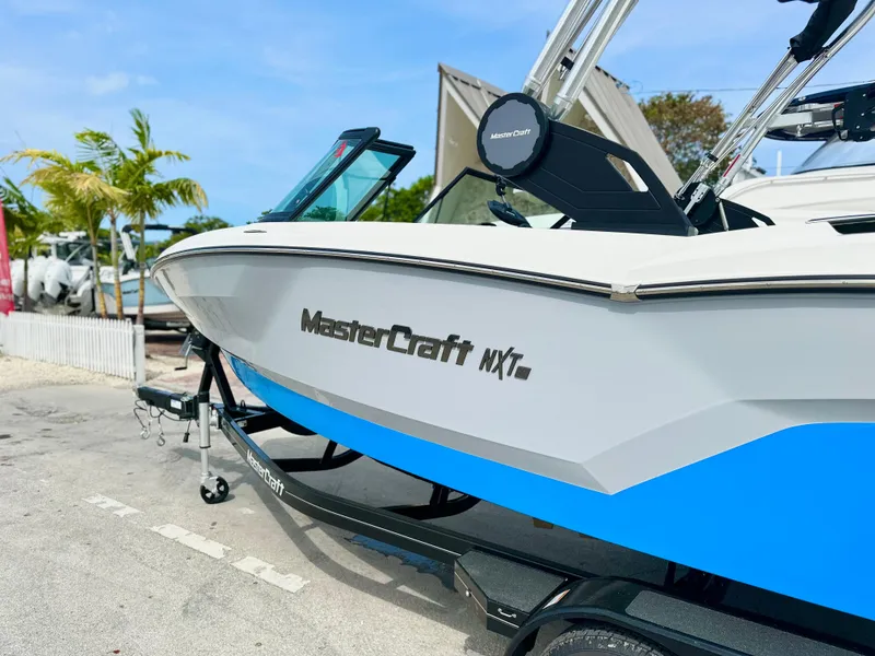 Slide: The Image of 2023 MasterCraft NXT21 boat with blue and white design on a trailer. - 3