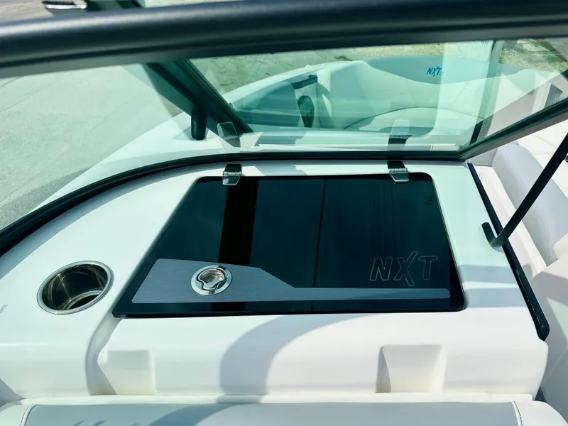 Slide: The Image of 2023 MasterCraft NXT21 boat dashboard with sleek black panel and cup holder. - 34