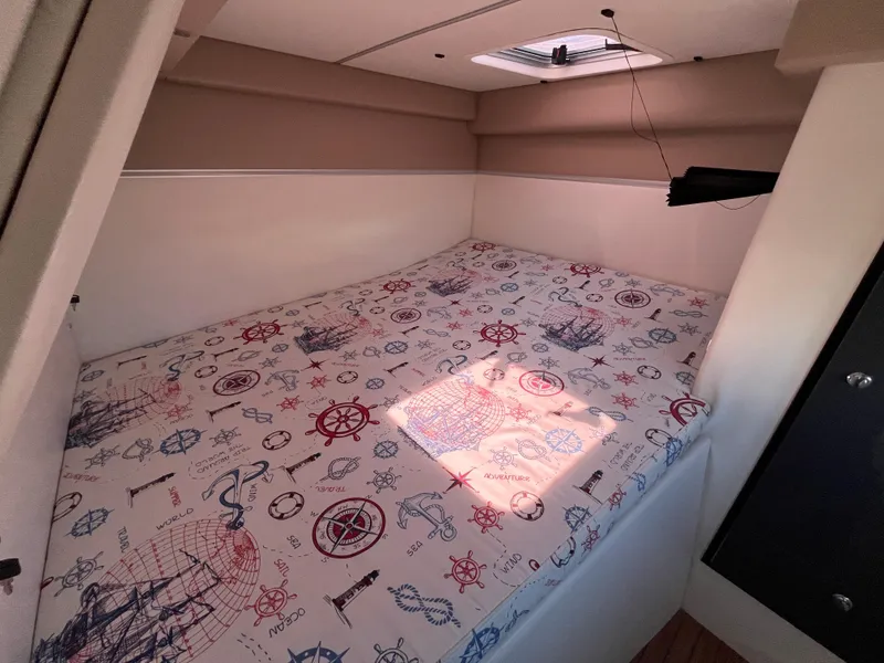 Slide: The Image of 2024 Tuna catamaran cabin with nautical-themed bedding and overhead hatch. - 16