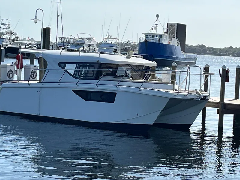 Slide: The Image of 2024 Tuna catamaran docked at a marina, surrounded by other boats. - 2
