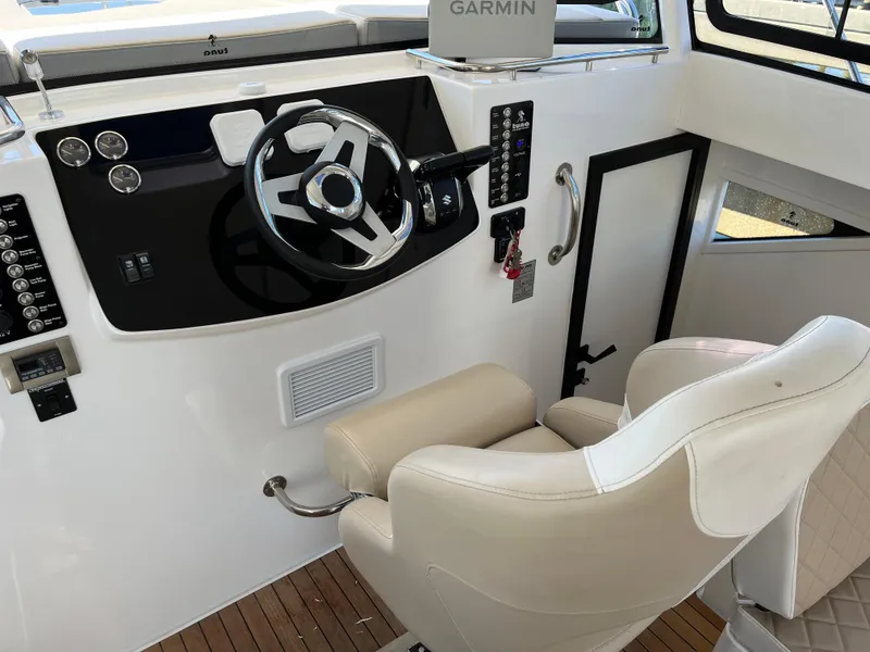 Slide: The Image of 2024 Tuna catamaran helm with steering wheel, control panel, and captain's chair. - 21