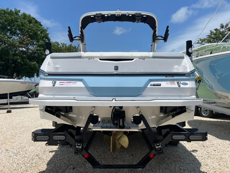 Slide: The Image of 2023 MasterCraft NXT23 boat rear view, showcasing sleek design and propeller, under a clear sky. - 9