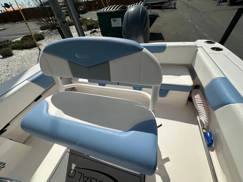 Slide: The Image of 2023 Robalo R202EX boat interior with blue and white seating, docked outdoors. - 10