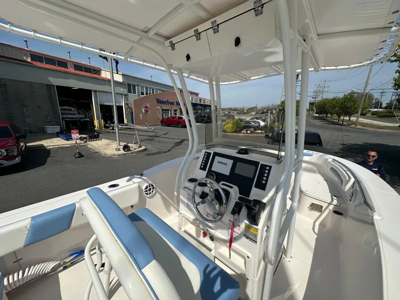 Slide: The Image of 2023 Robalo R202EX boat interior with steering console and seating, parked near a dealership. - 19