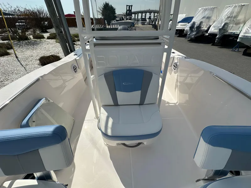 Slide: The Image of 2023 Robalo R202EX boat interior with blue and white seating, docked outdoors. - 23