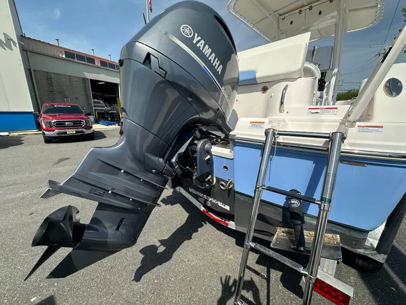 Slide: The Image of 2023 Robalo R202EX boat with Yamaha outboard motor and ladder, parked outdoors. - 6