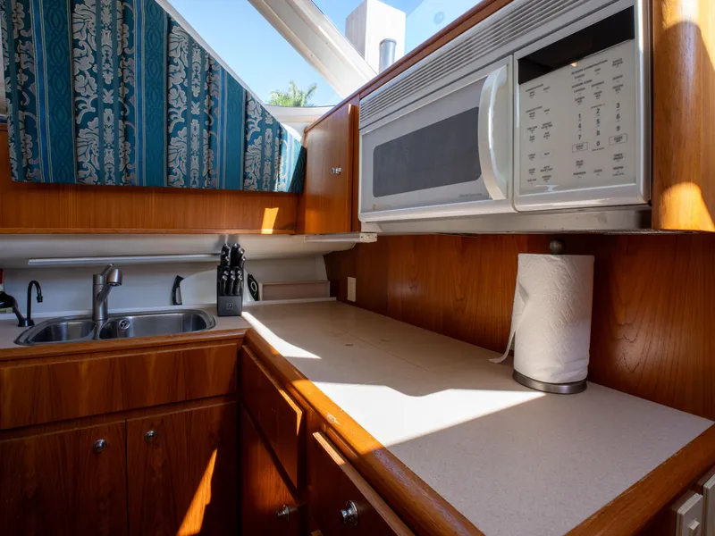 Slide: The Image of Kitchen area of 2000 Tiara Yachts 4300 Convertible with sink, microwave, and wooden cabinetry. - 18