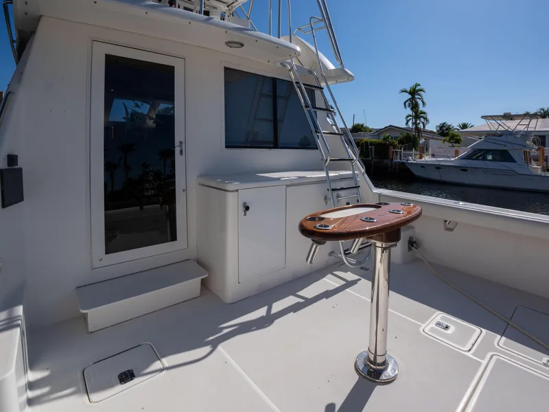 Slide: The Image of 2000 Tiara Yachts 4300 Convertible deck with ladder, fishing station, and marina view. - 2