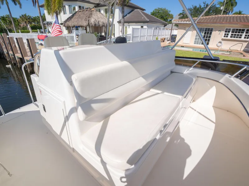 Slide: The Image of 2000 Tiara Yachts 4300 Convertible with white seating on deck, docked near waterfront homes. - 7