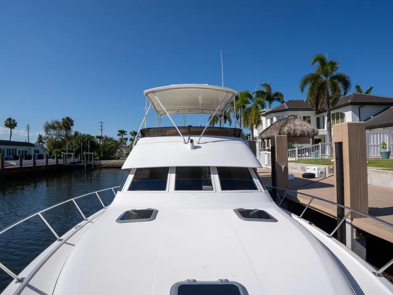 Slide: The Image of 2000 Tiara Yachts 4300 Convertible docked near waterfront homes, clear blue sky. - 9
