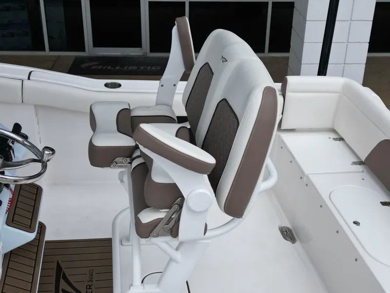 Slide: The Image of 2025 Tidewater 232LXF boat seating with brown and white cushioned helm chairs. - 19