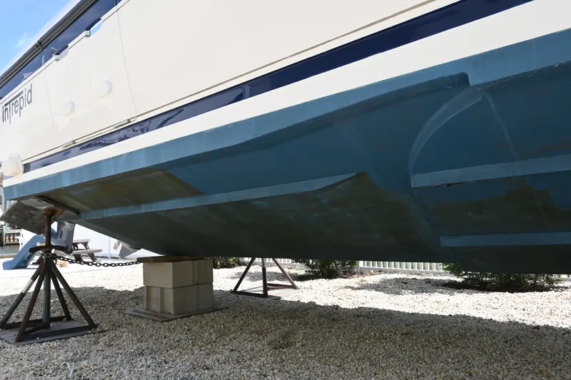 Slide: The Image of 2002 Intrepid 323 Cuddy boat hull on stands, displayed outdoors. - 15