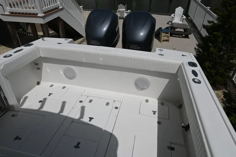 Slide: The Image of 2002 Intrepid 323 Cuddy boat deck with twin engines, spacious layout, and storage compartments. - 22