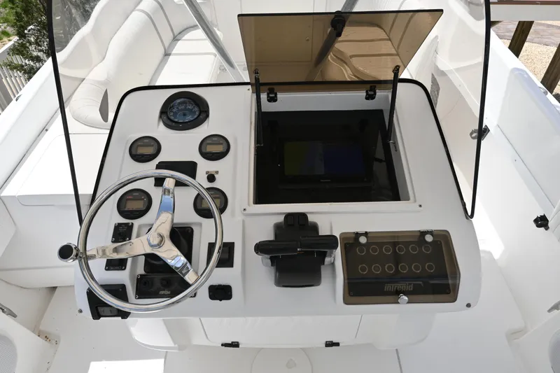 Slide: The Image of 2002 Intrepid 323 Cuddy boat dashboard with steering wheel and control panel. - 25