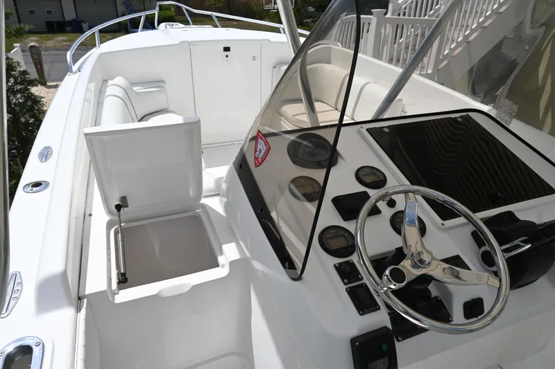 Slide: The Image of 2002 Intrepid 323 Cuddy boat interior with steering wheel and open storage compartment. - 32