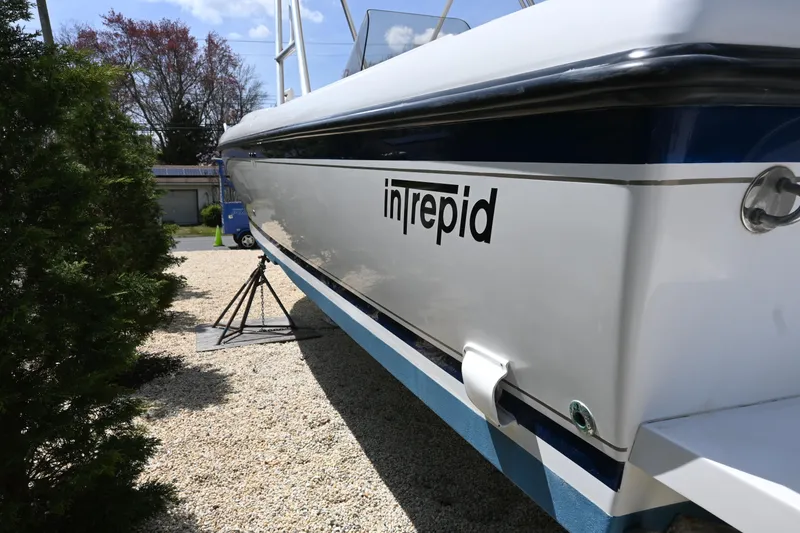 Slide: The Image of 2002 Intrepid 323 Cuddy boat side view, displayed outdoors on gravel. - 4