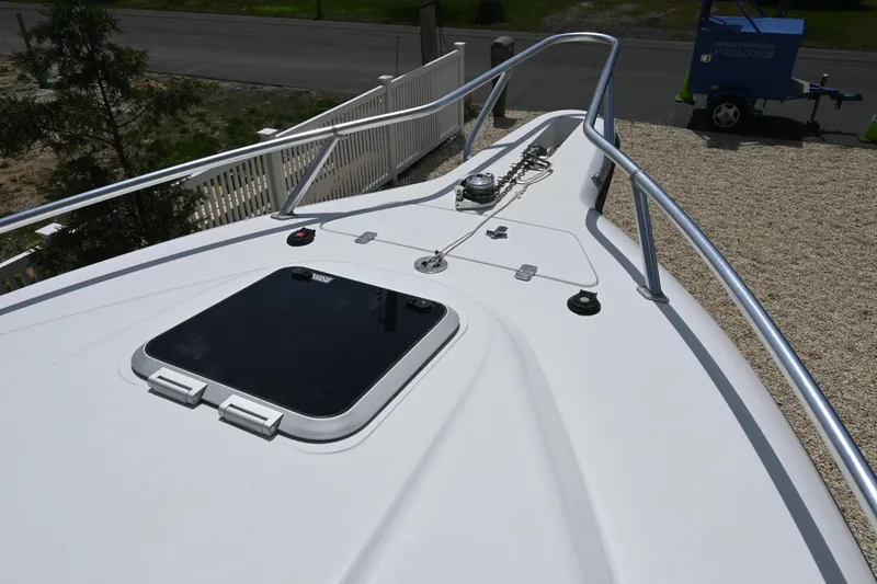 Slide: The Image of 2002 Intrepid 323 Cuddy boat deck with hatch and railing, parked on gravel. - 41