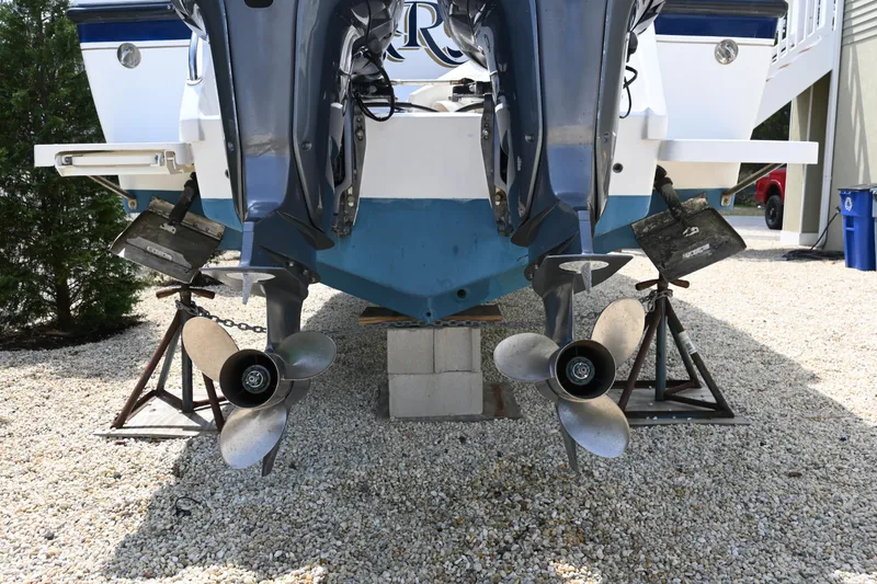 Slide: The Image of Rear view of a 2002 Intrepid 323 Cuddy boat with dual propellers on stands. - 5