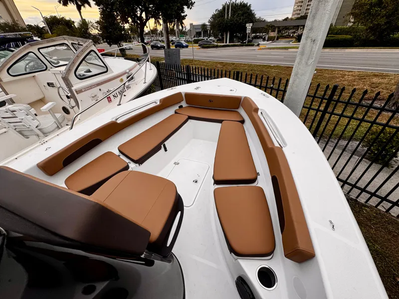 Slide: The Image of 2025 Sea Pro 202 Center Console boat with brown seating, docked near a fence. - 15