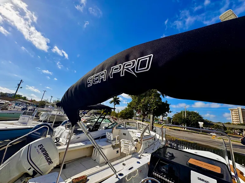 Slide: The Image of 2025 Sea Pro 202 Center Console boat with canopy, parked under a clear blue sky. - 26