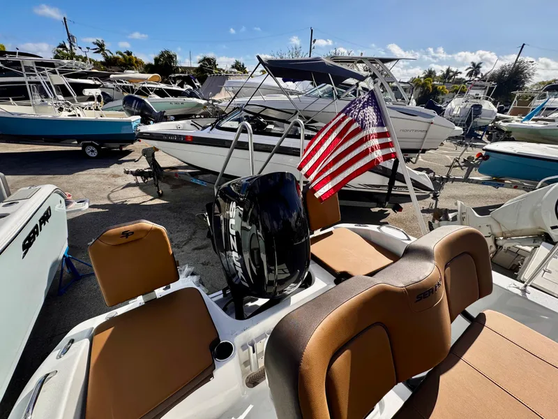Slide: The Image of 2025 Sea Pro 202 Center Console boat with American flag, parked in a marina. - 4