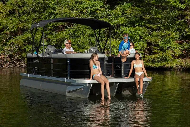 Slide: The Image of 2024 Veranda Vista 20RC pontoon boat with people relaxing on a calm lake. - 14