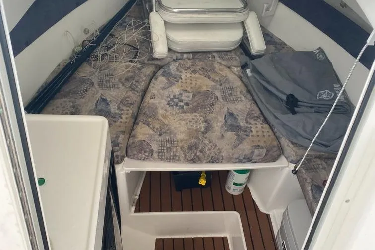 Slide: The Image of 2004 Cobia 270 Walk-Around cabin interior with patterned cushions and wooden flooring. - 8