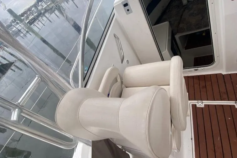 Slide: The Image of 2004 Cobia 270 Walk-Around boat interior with white seating and wooden flooring. - 9