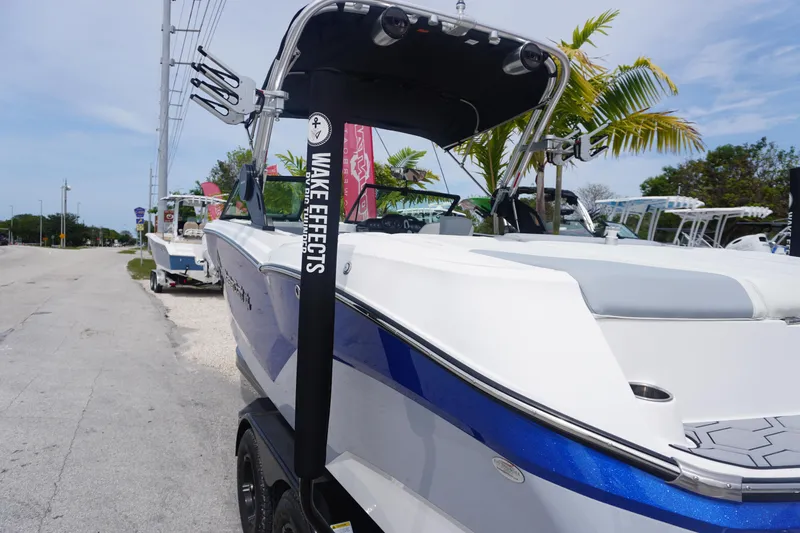 Slide: The Image of 2023 MasterCraft NXT24 boat with blue accents parked near palm trees. - 34