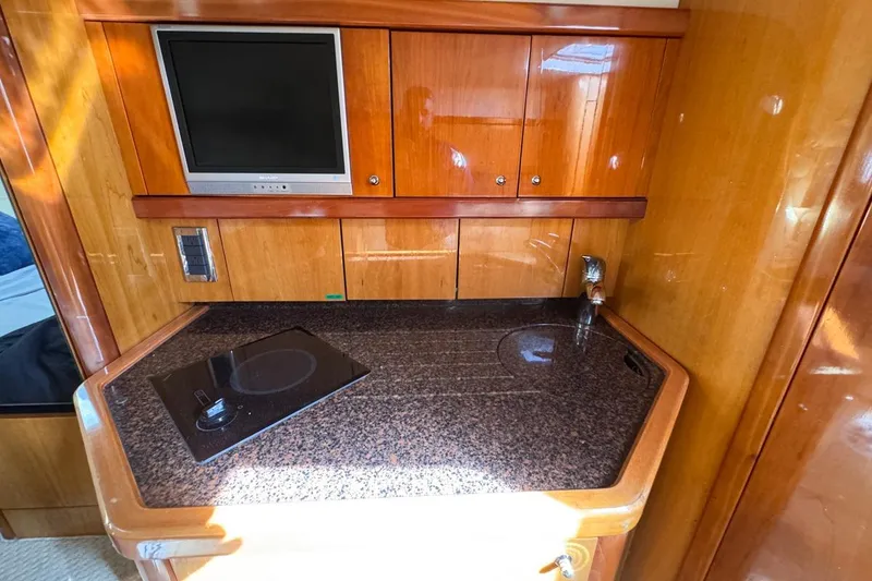 Slide: The Image of 2004 Sunseeker Sportfisher 37 yacht interior with kitchenette, TV, and wooden cabinetry. - 104