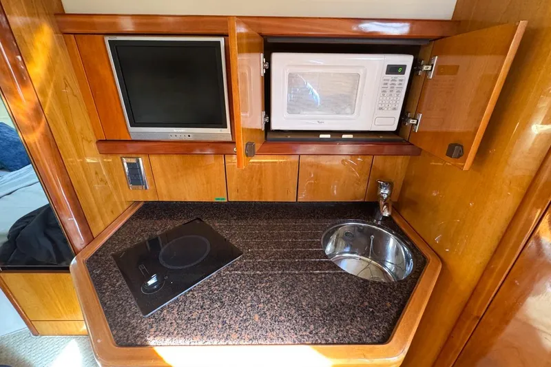 Slide: The Image of Compact kitchen area in 2004 Sunseeker Sportfisher 37 with microwave, sink, and cooktop. - 105