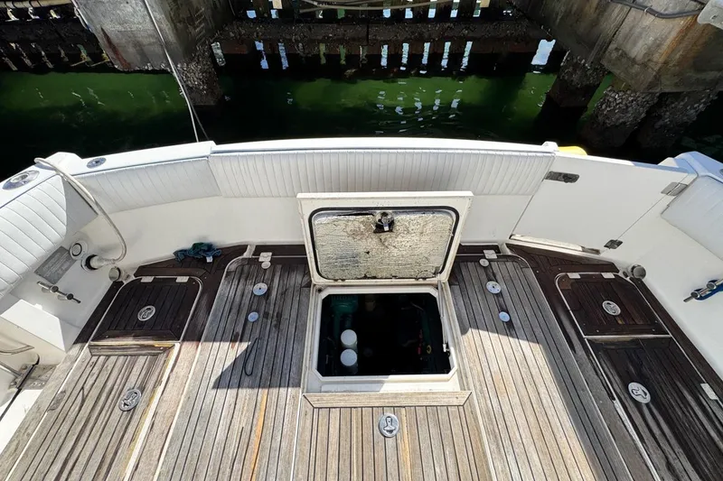 Slide: The Image of 2004 Sunseeker Sportfisher 37 boat deck with open hatch, wooden flooring, and white seating. - 72