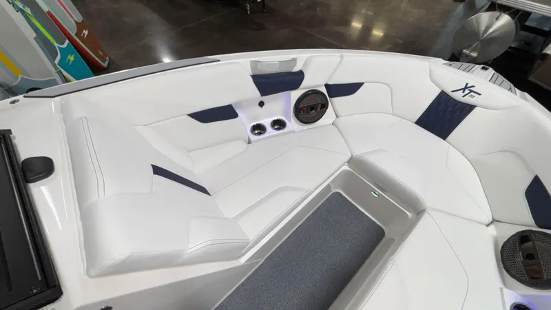 Slide: The Image of 2025 MasterCraft XT23 boat interior with white and navy seating, featuring speakers and cup holders. - 13