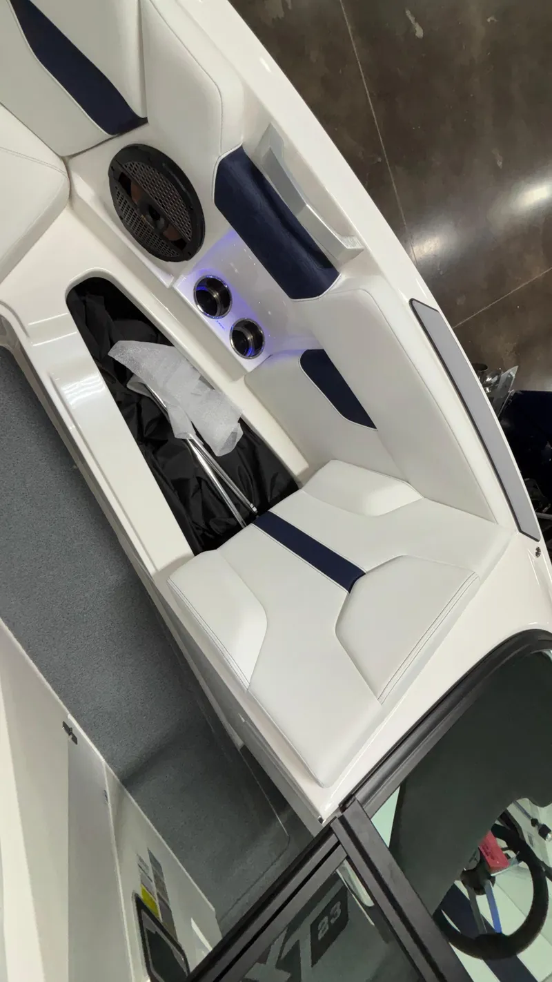 Slide: The Image of 2025 MasterCraft XT23 boat interior with white and navy seating, speaker, and cup holders. - 24