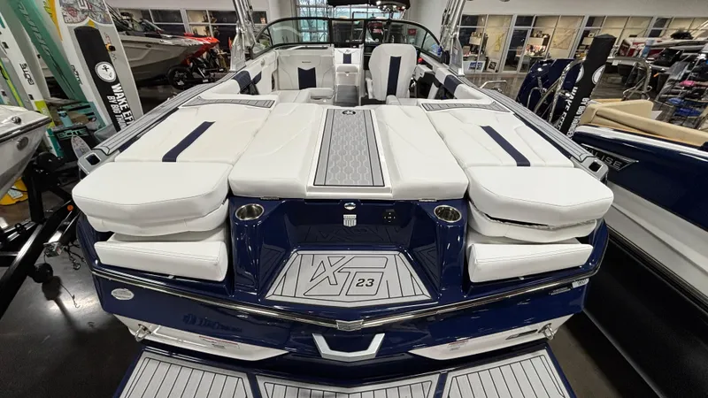 Slide: The Image of 2025 MasterCraft XT23 boat with sleek design and luxurious seating in showroom. - 28