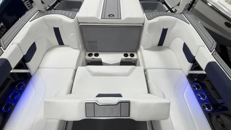 Slide: The Image of 2025 MasterCraft XT23 boat interior with white and blue seating, cup holders, and ambient lighting. - 33