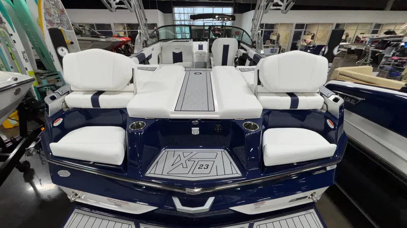 Slide: The Image of 2025 MasterCraft XT23 boat with white seating and blue accents in showroom. - 35