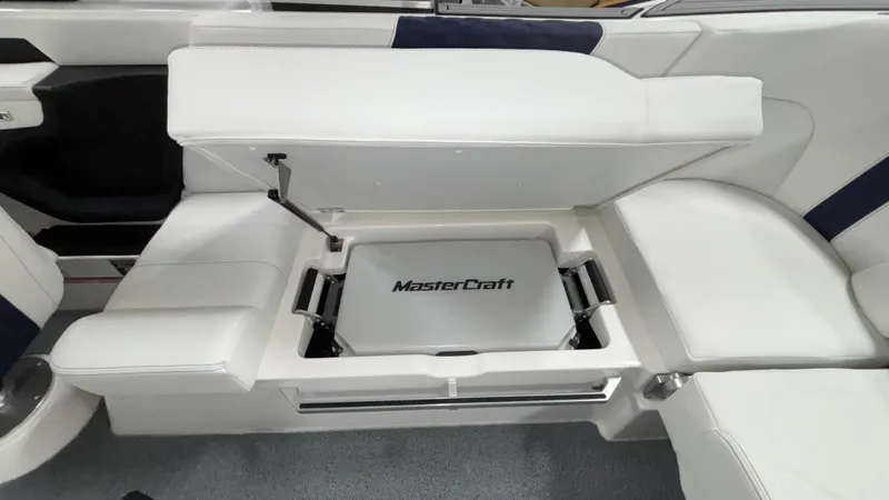 Slide: The Image of 2025 MasterCraft XT23 boat interior with open storage compartment and white seating. - 37