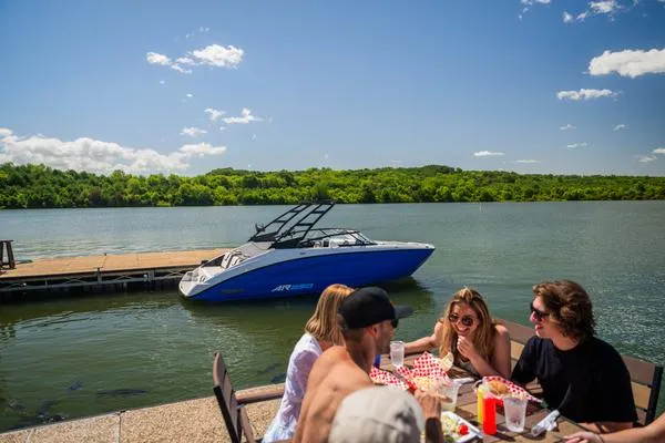 Slide: The Image of People dining by a lake with a 2025 Yamaha AR250 boat docked nearby. - 4
