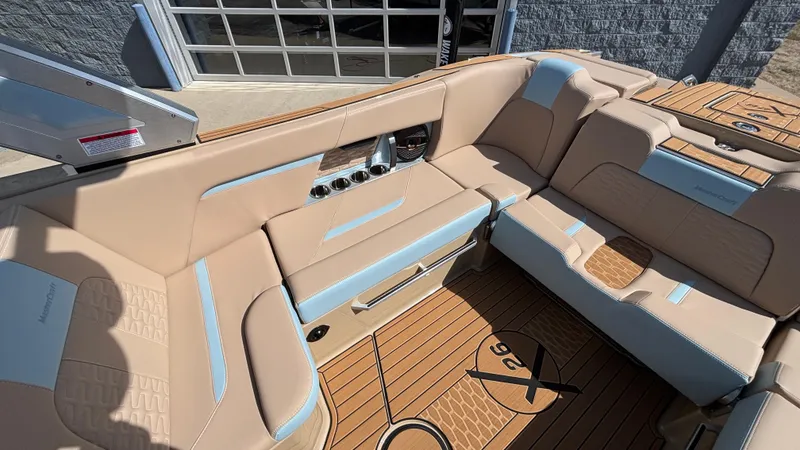 Slide: The Image of 2025 MasterCraft X26 boat interior with beige and blue seating, featuring teak flooring. - 10