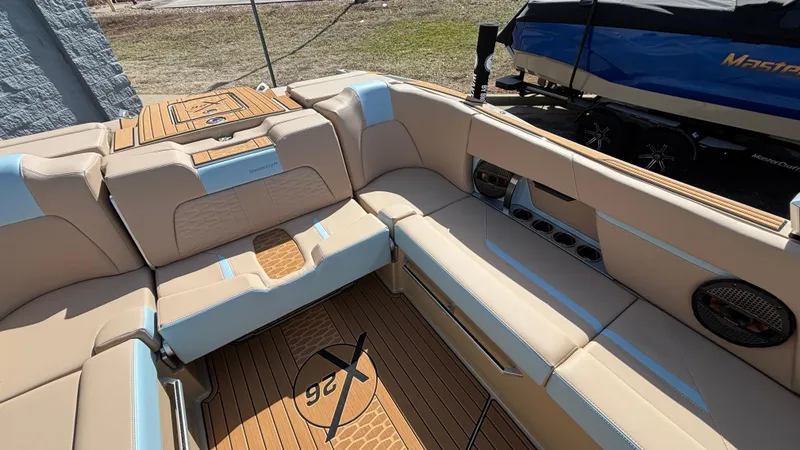 Slide: The Image of 2025 MasterCraft X26 boat interior with beige seating and wood accents. - 11